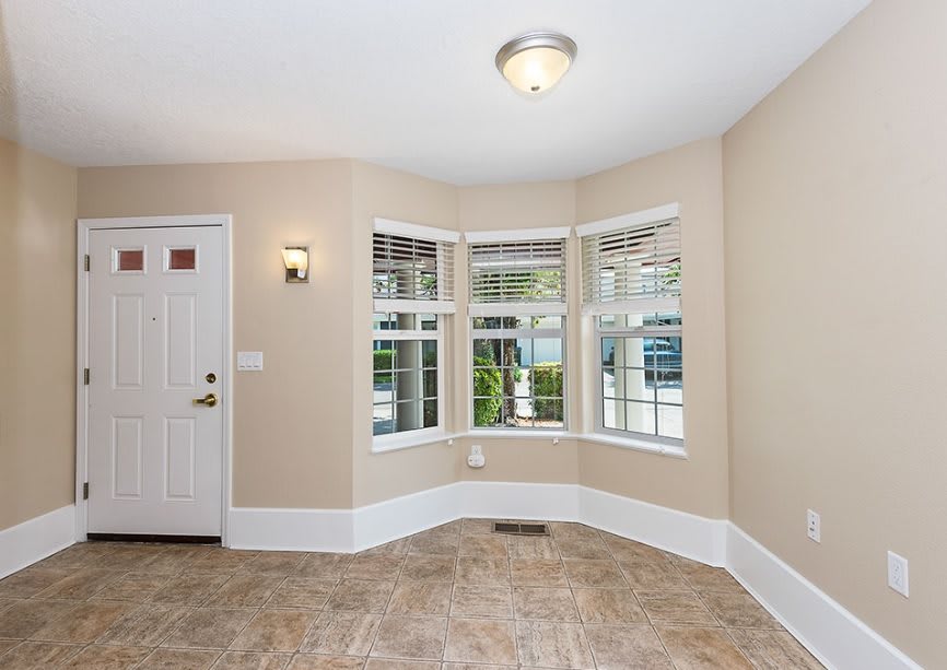 A bright living room with a bay window and tiled flooring.