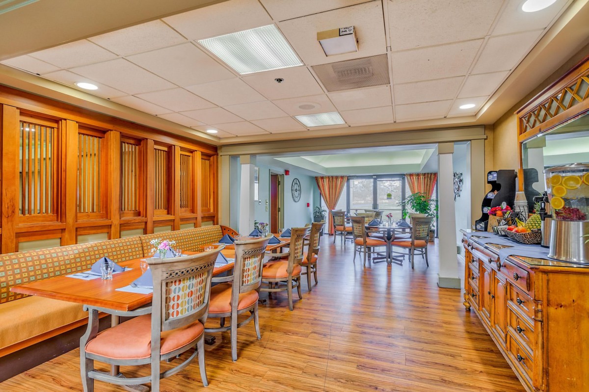 A cozy dining area with wooden flooring and neatly arranged tables and chairs.