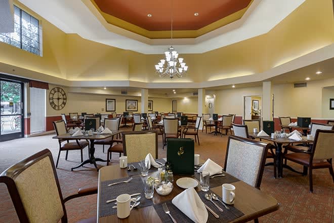A spacious dining area with neatly arranged tables and a central chandelier.