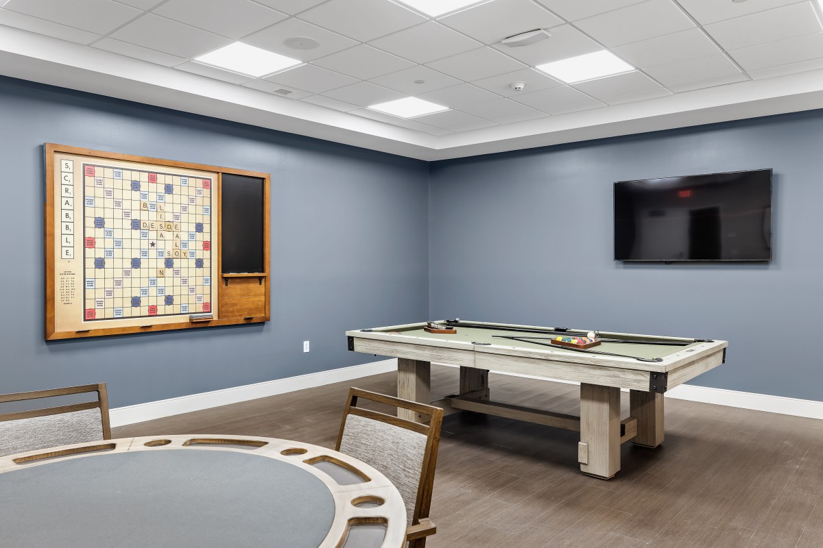 A modern game room featuring a pool table and a wall-mounted Scrabble board.