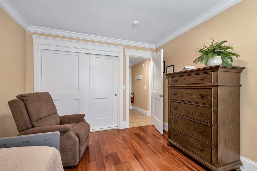 A cozy bedroom featuring a large dresser, comfortable chair, and spacious closet with sliding doors.