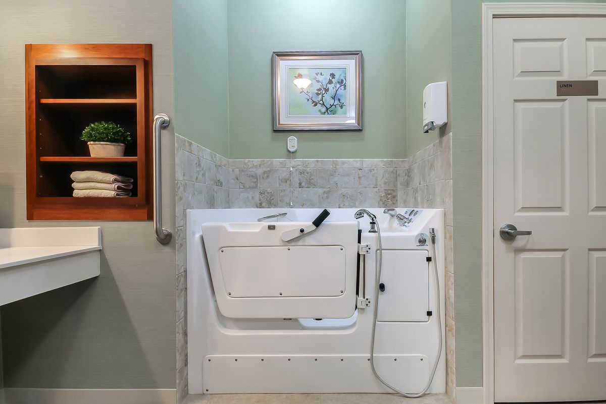 A bathroom featuring an accessible walk-in bathtub with tiled walls.