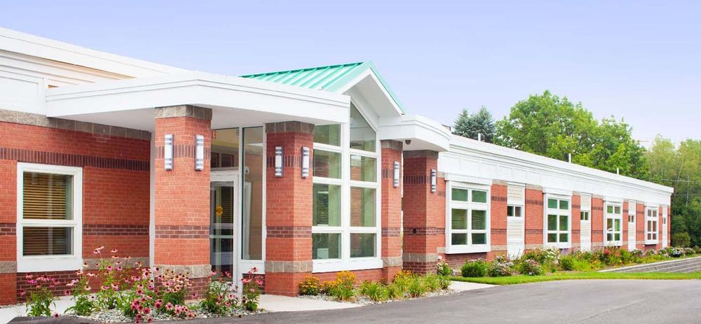 A modern brick building exterior with large windows and a green roof.