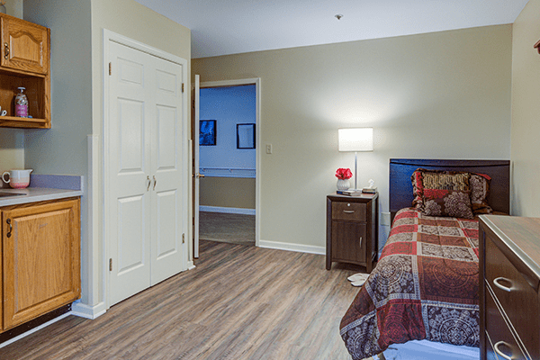 A cozy bedroom with a neatly made bed, nightstand, and a lamp.