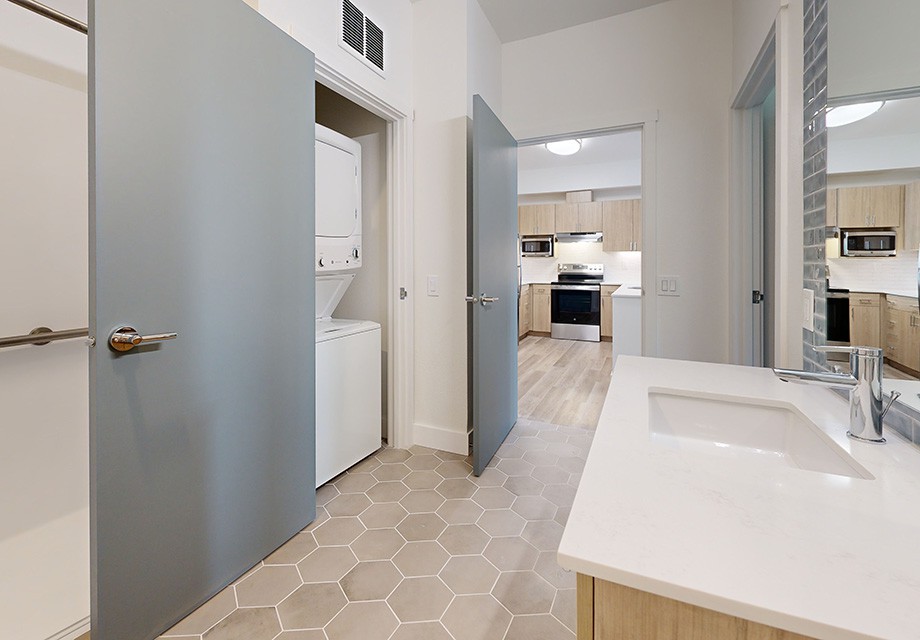 Modern interior with a laundry area and kitchen visible from the hallway.