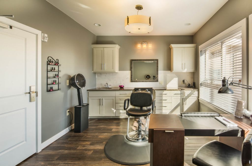 A modern and well-lit beauty salon with stylish furniture and a barber chair.