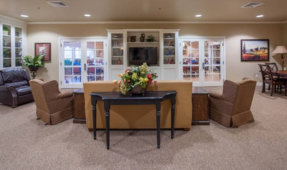 A cozy living room with a sofa, table, and television, adorned with floral decorations.