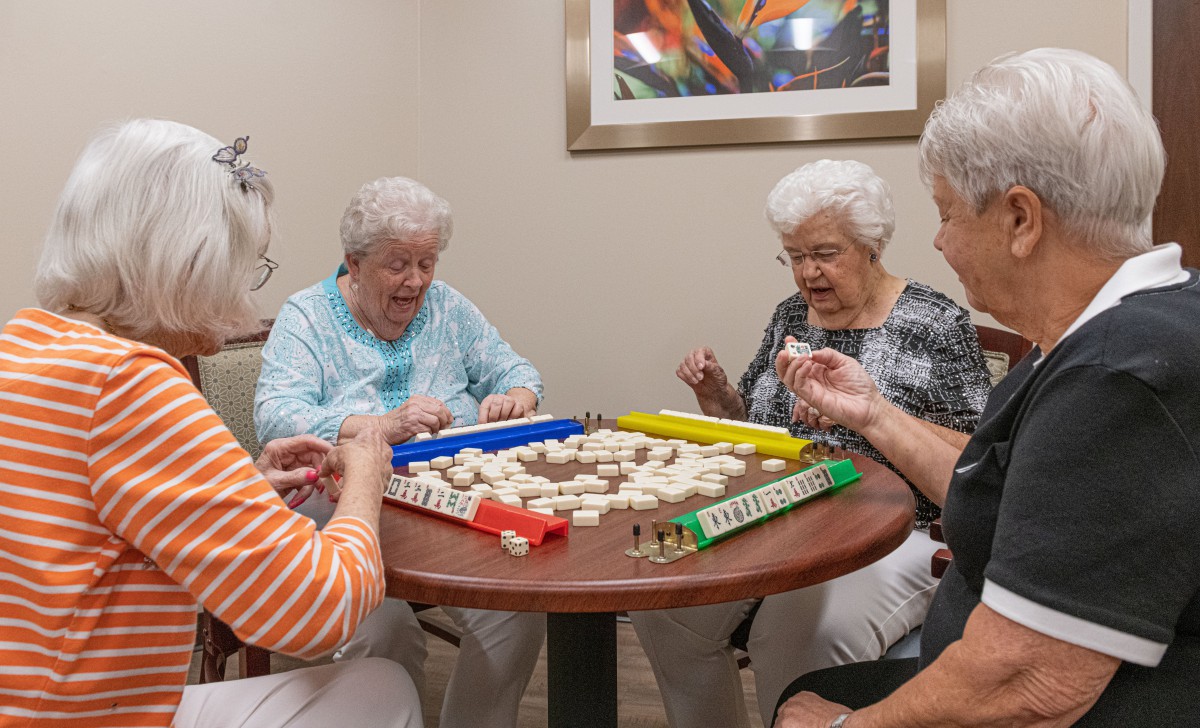 A group of seniors enjoying a game of Mahjong indoors.