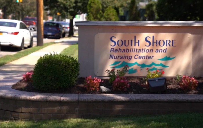 Entrance sign for South Shore Rehabilitation and Nursing Center surrounded by flowers and shrubs.