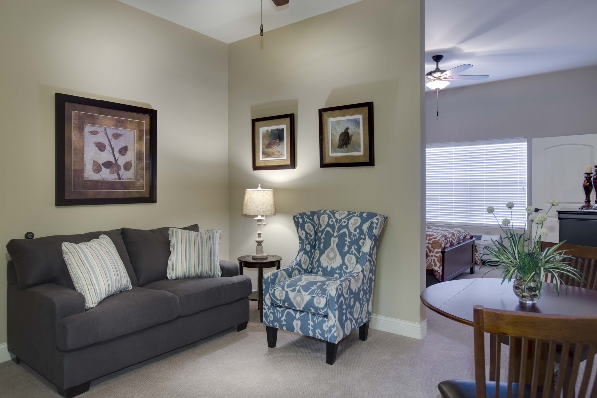 A cozy living room featuring a gray sofa, a patterned armchair, and warm lighting.