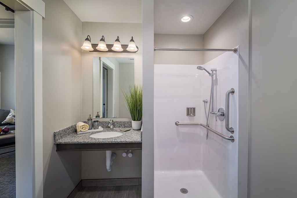 A modern bathroom featuring a sleek vanity with a mirror and a separate shower area.