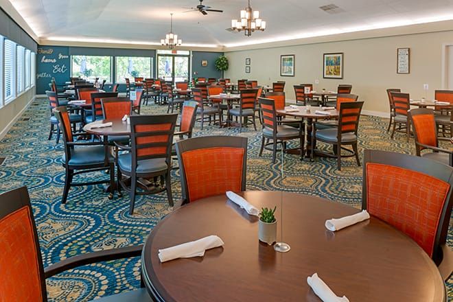 An elegant dining area with neatly arranged tables and chairs, adorned with a stylish carpet and large windows providing natural light.