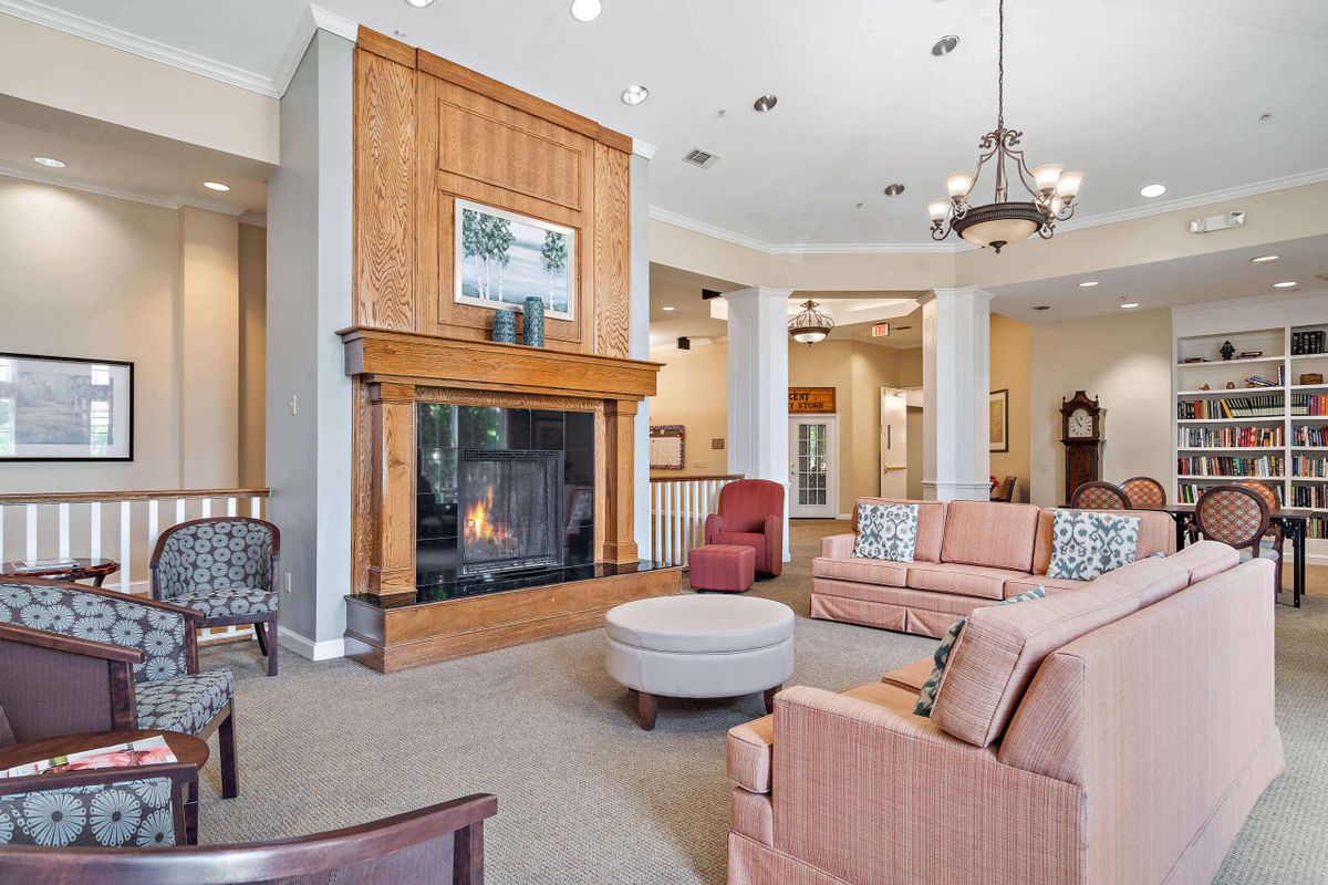 A spacious and elegantly designed living room with a fireplace, multiple sofas, and a chandelier.
