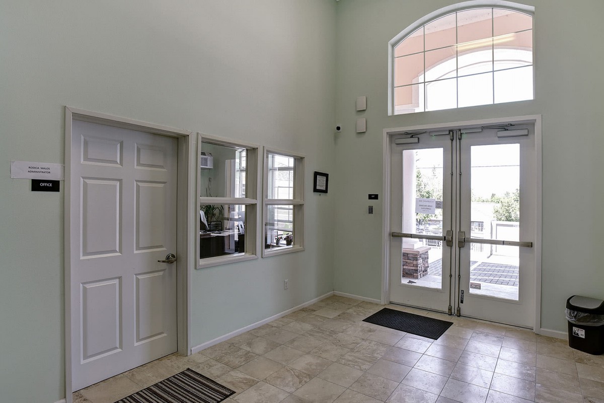 A bright and welcoming lobby entrance with large windows and tile flooring.
