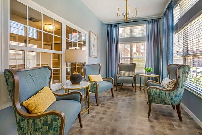 A cozy living room with elegant chairs, blue curtains, and a chandelier.