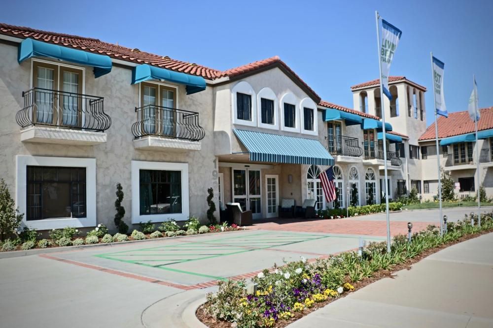A sunny day view of a hotel with a tiled roof and floral decorations at the entrance.