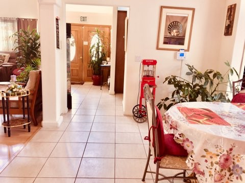 A cozy dining area with a tiled floor, adorned with indoor plants and artwork, featuring a decorative popcorn machine.