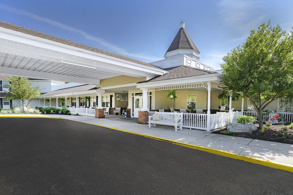 A scenic view of a building entrance with a covered porch and distinctive roof structure against a clear blue sky.