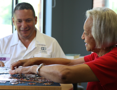Two individuals enjoy a puzzle together, sharing smiles and conversation.