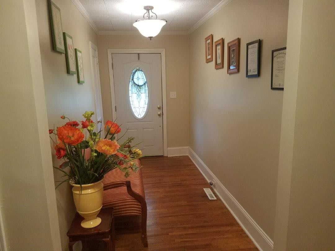A welcoming hallway with floral decorations and framed artwork.