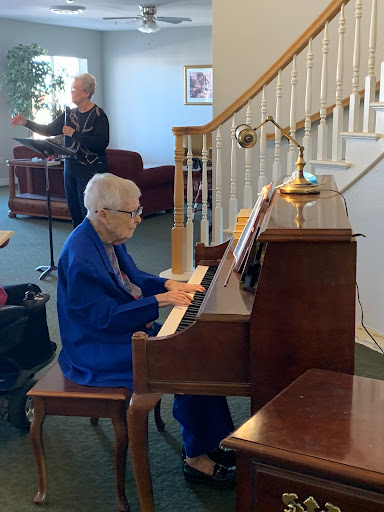 An elderly person playing the piano in a cozy indoor setting.
