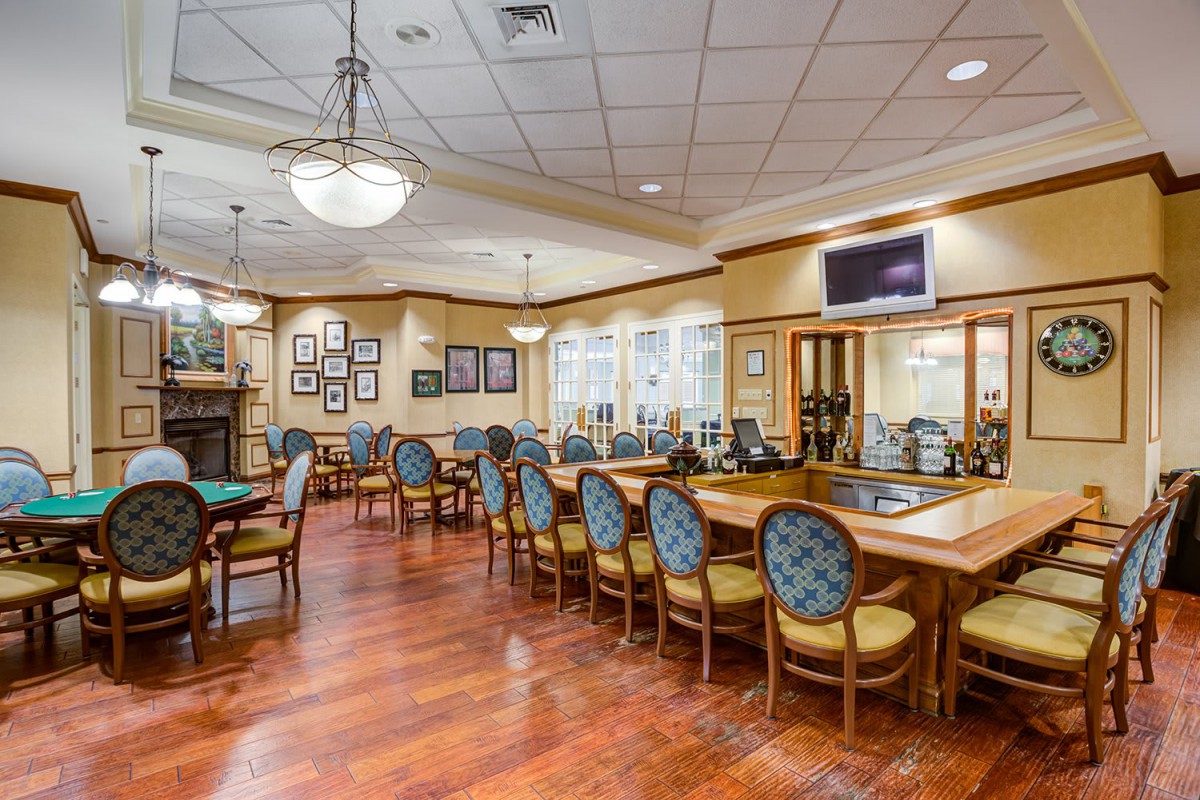 A spacious dining area with elegant decor, featuring multiple tables and chairs, wood flooring, and a chandelier.