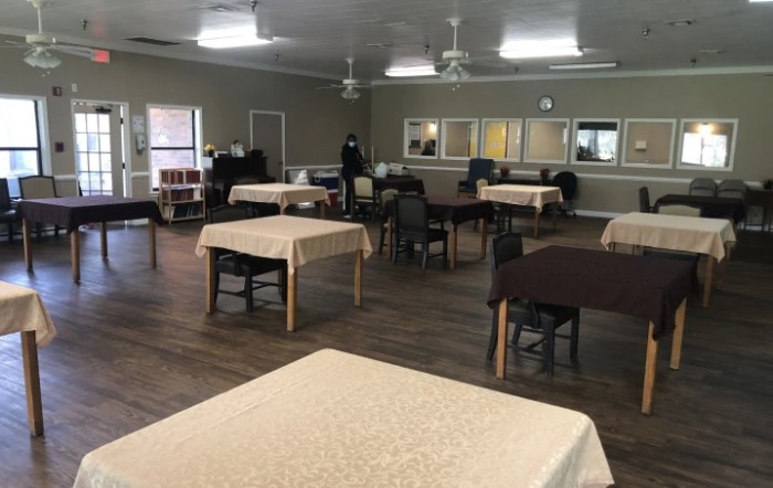 An empty dining hall with neatly arranged tables and chairs.