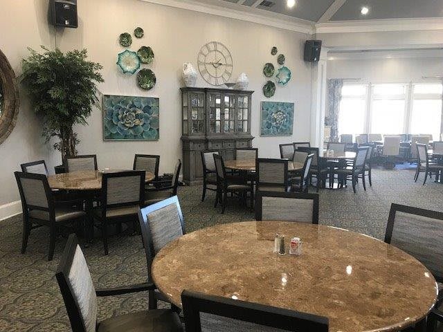 A spacious dining area with neatly arranged tables and chairs, decorated with wall art and plants.