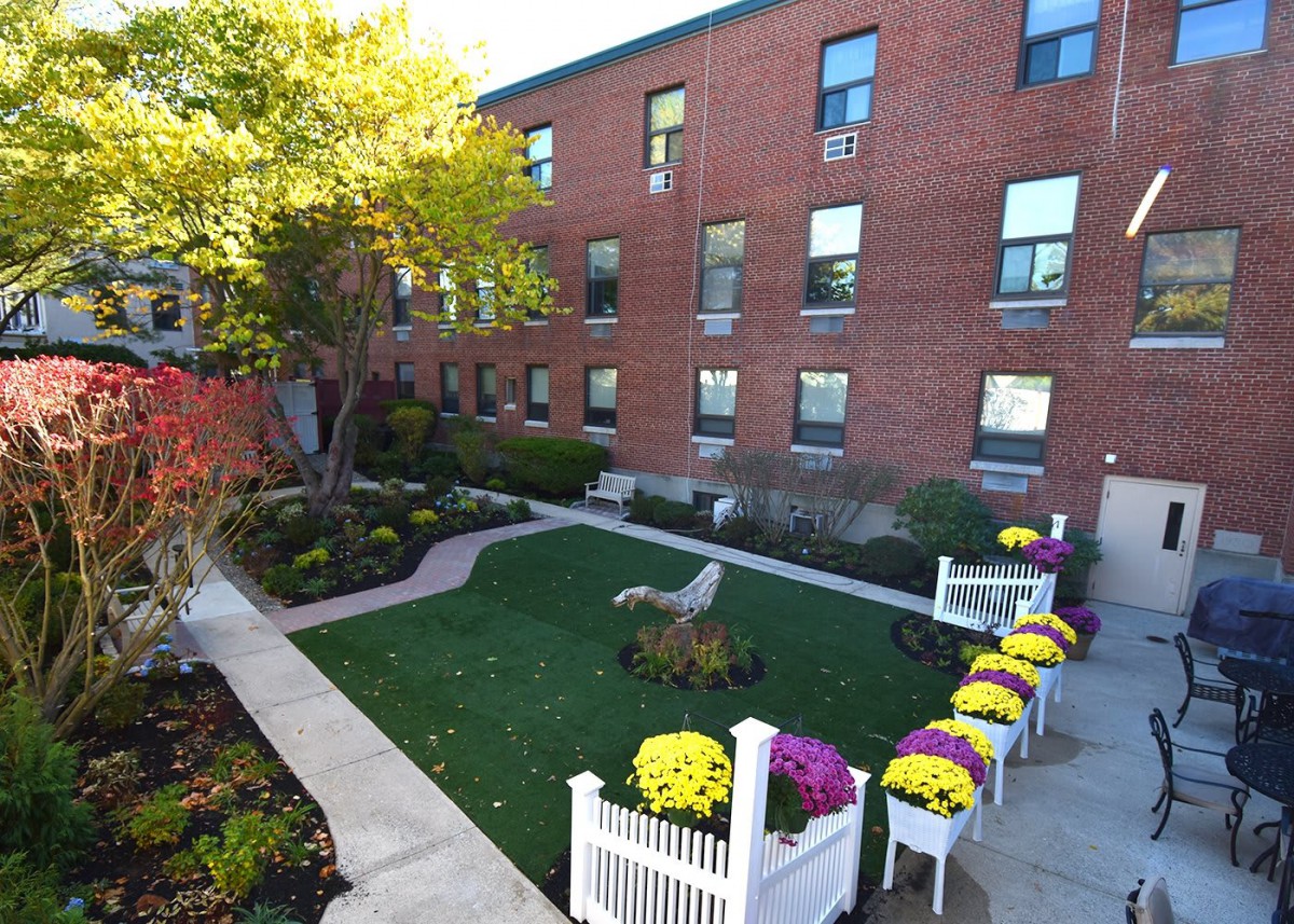 A well-maintained courtyard garden with vibrant flowers and a brick building backdrop.