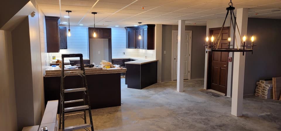 A modern basement kitchen under renovation with stylish cabinets and lighting.