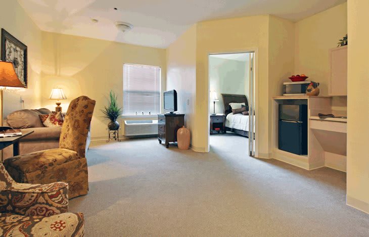 A cozy living space connecting to a bedroom, featuring comfortable furniture and a television.