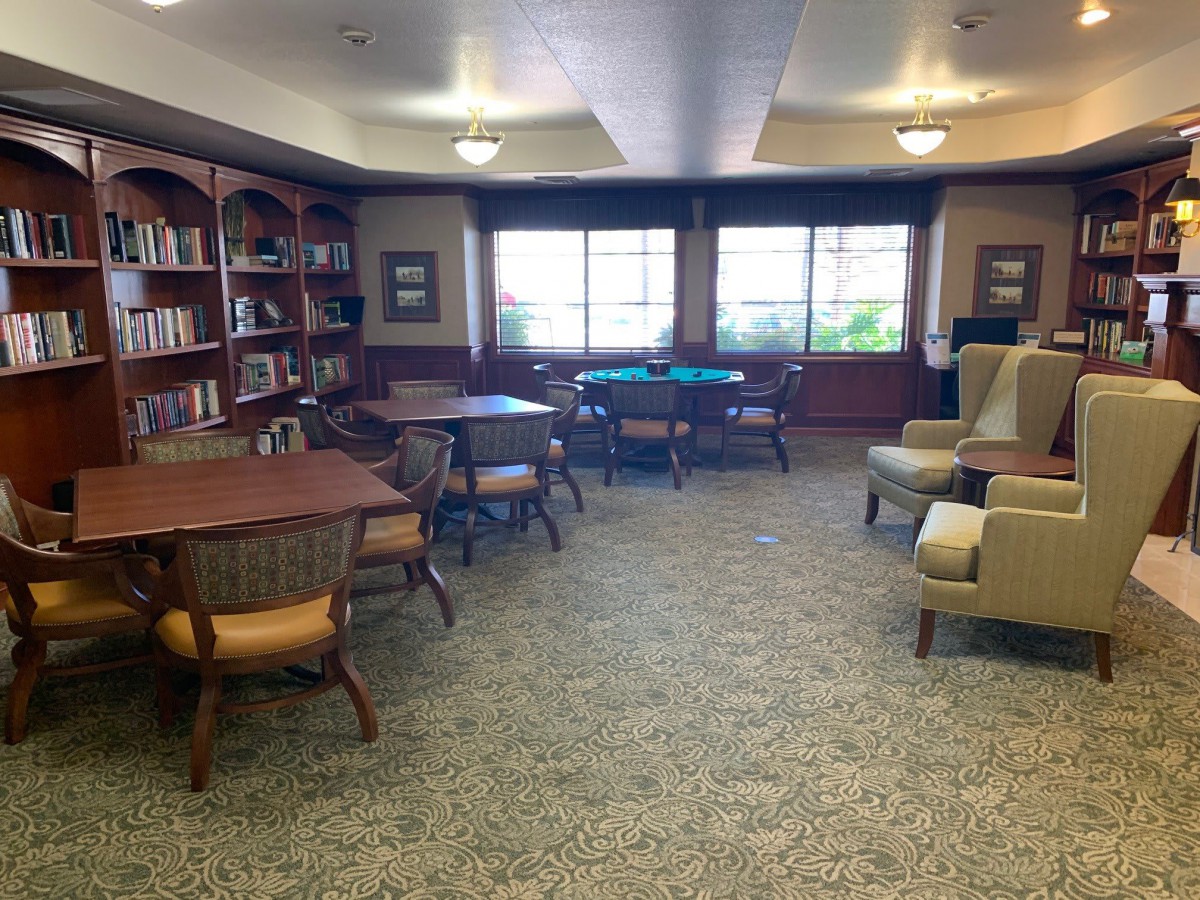 A cozy library reading room with bookshelves, tables, and chairs.