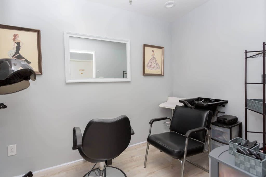 A minimalist hair salon interior featuring chairs, a mirror, and a washing sink.