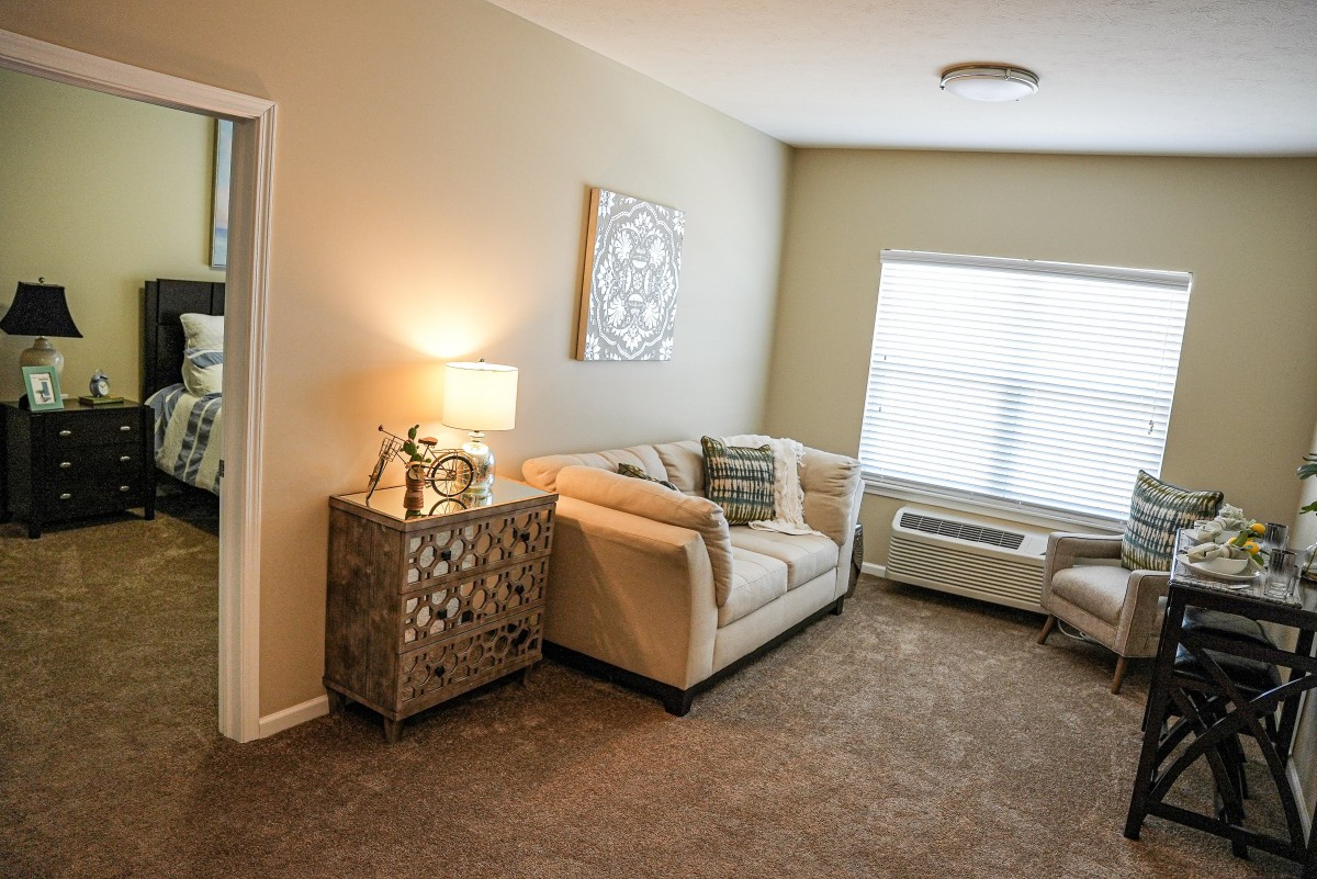 A cozy living room with a sofa and lamp next to a decorative table.