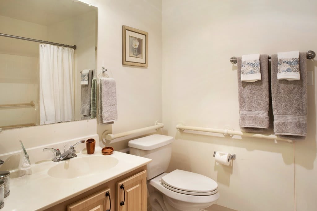 A clean and simple bathroom with a sink, toilet, and hanging towels.