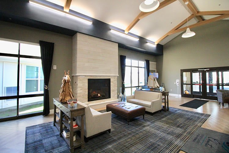 A modern living room with a cozy fireplace and ample seating, featuring large windows and stylish decor.