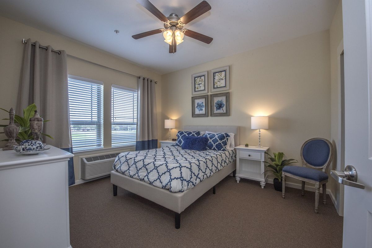 A modern bedroom interior featuring a neatly made bed, stylish decor, and natural light from large windows.