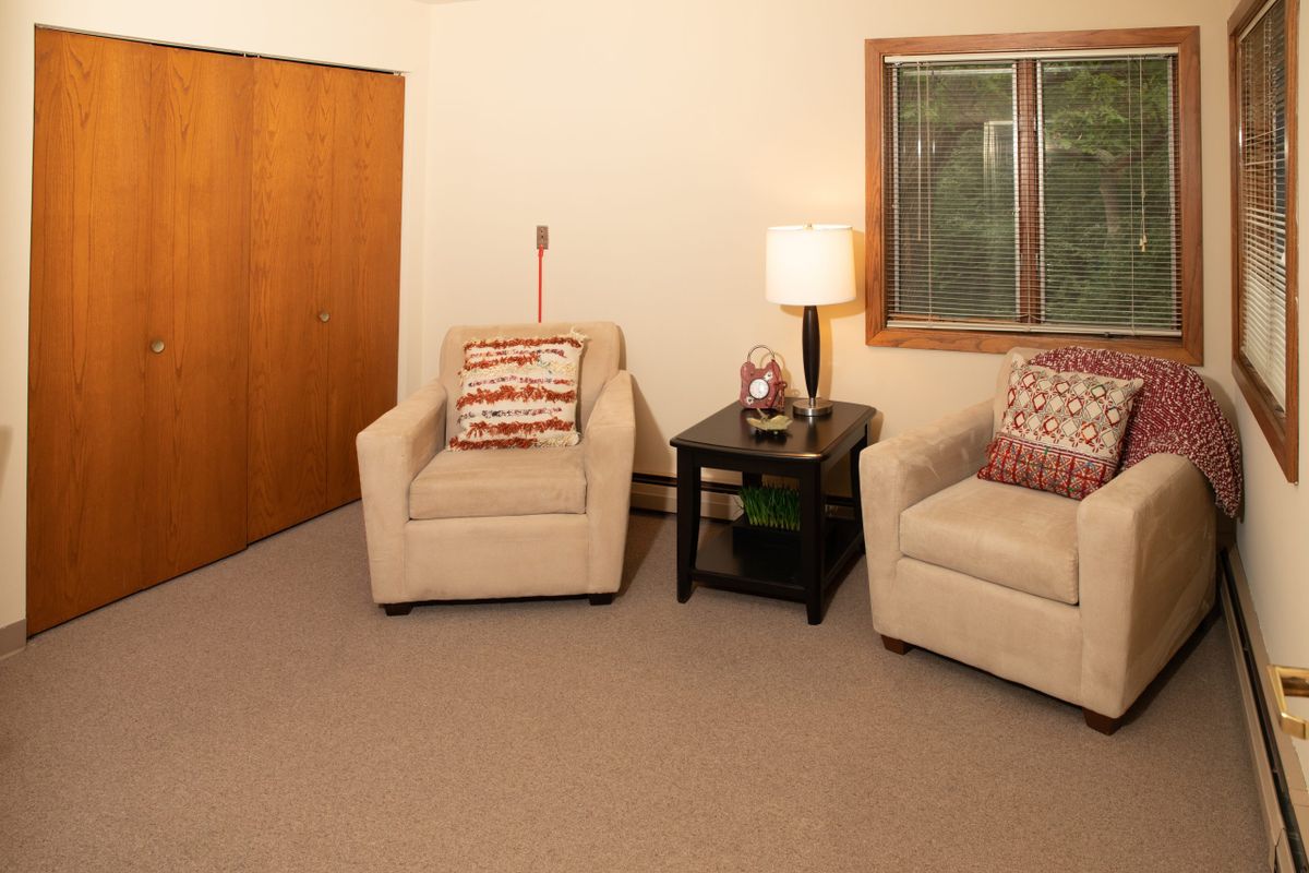A cozy living room with two armchairs, a side table, and a lamp.