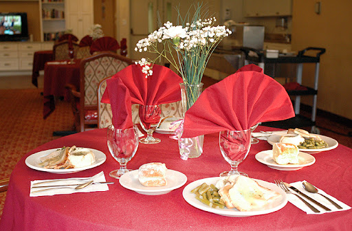 An elegantly set dining table featuring red napkins, decorative flowers, and delicious meals.