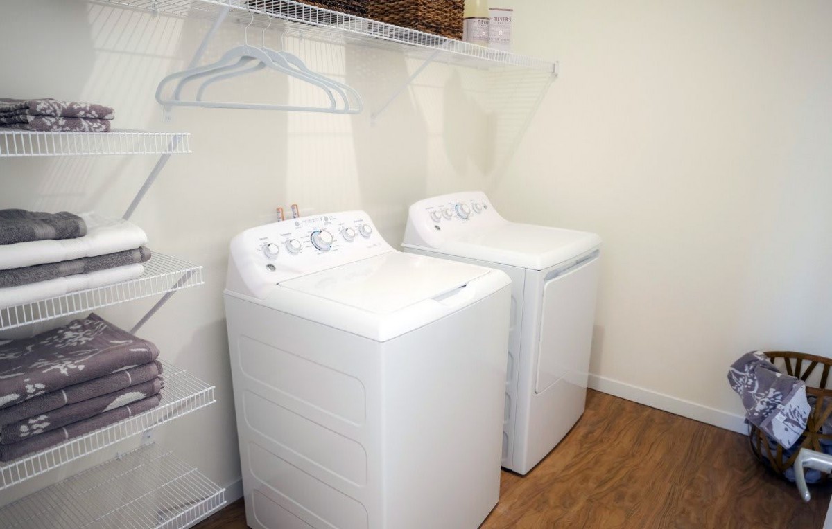 A laundry room featuring a washing machine and dryer with shelving above.