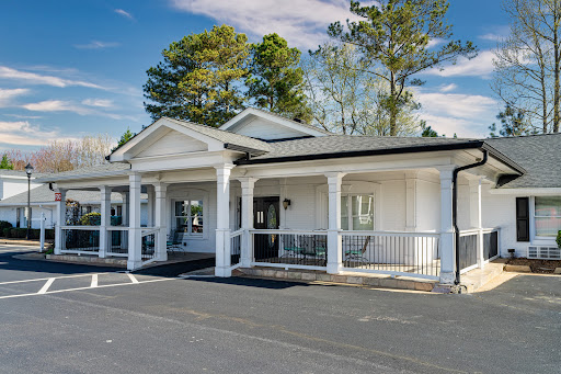 A charming white building with a front porch, surrounded by trees.