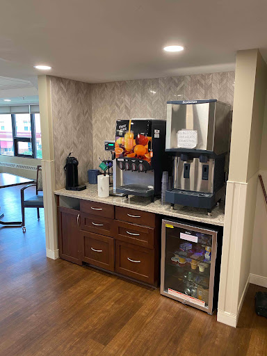 A modern beverage station featuring a coffee maker, water dispenser, and refrigerator in a well-designed kitchen area.