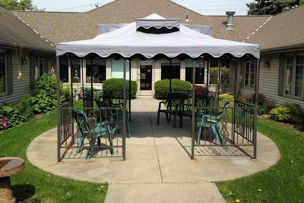 A patio area with a canopy and garden chairs.