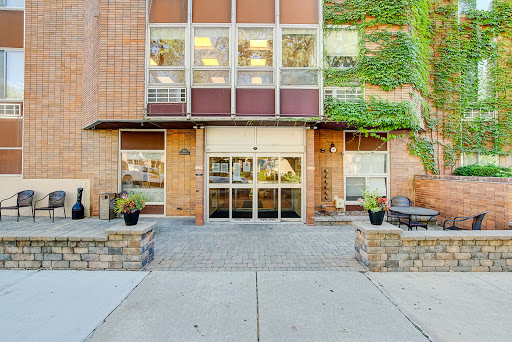 Front view of a modern building with greenery and inviting entrance.