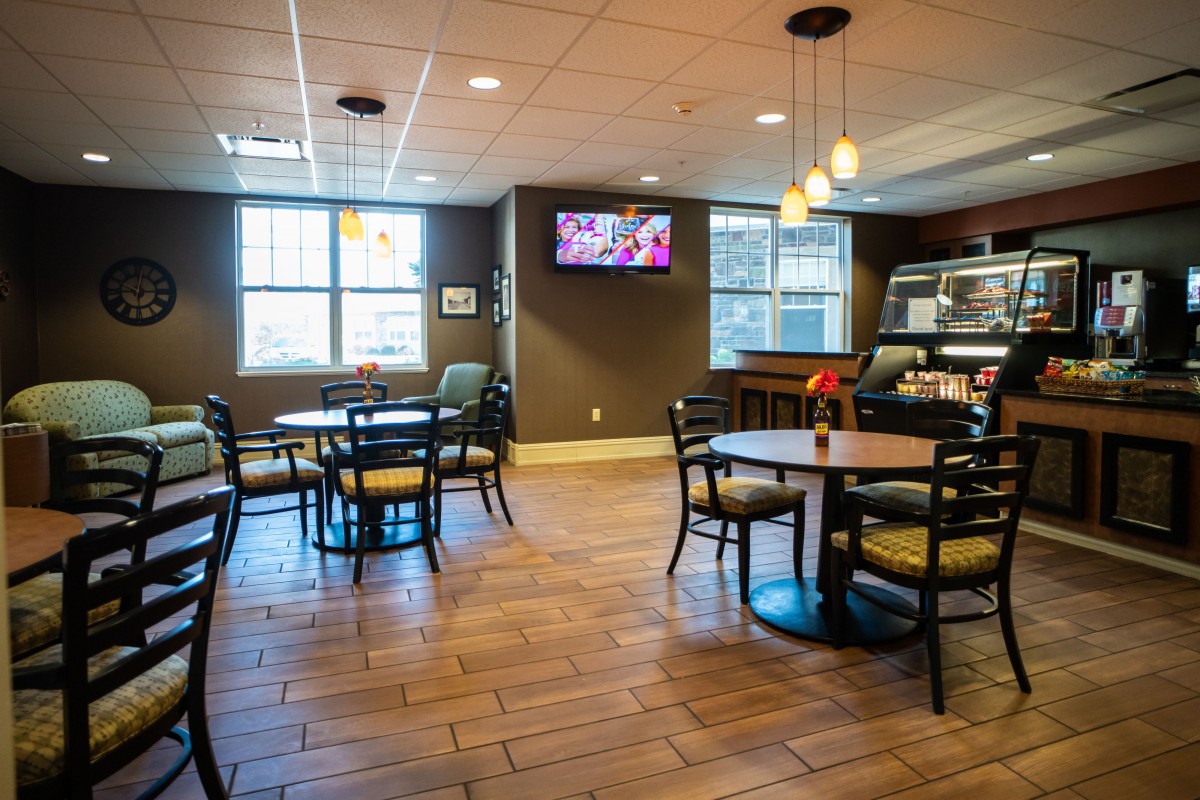 A cozy cafe interior with tables, chairs, and warm lighting.