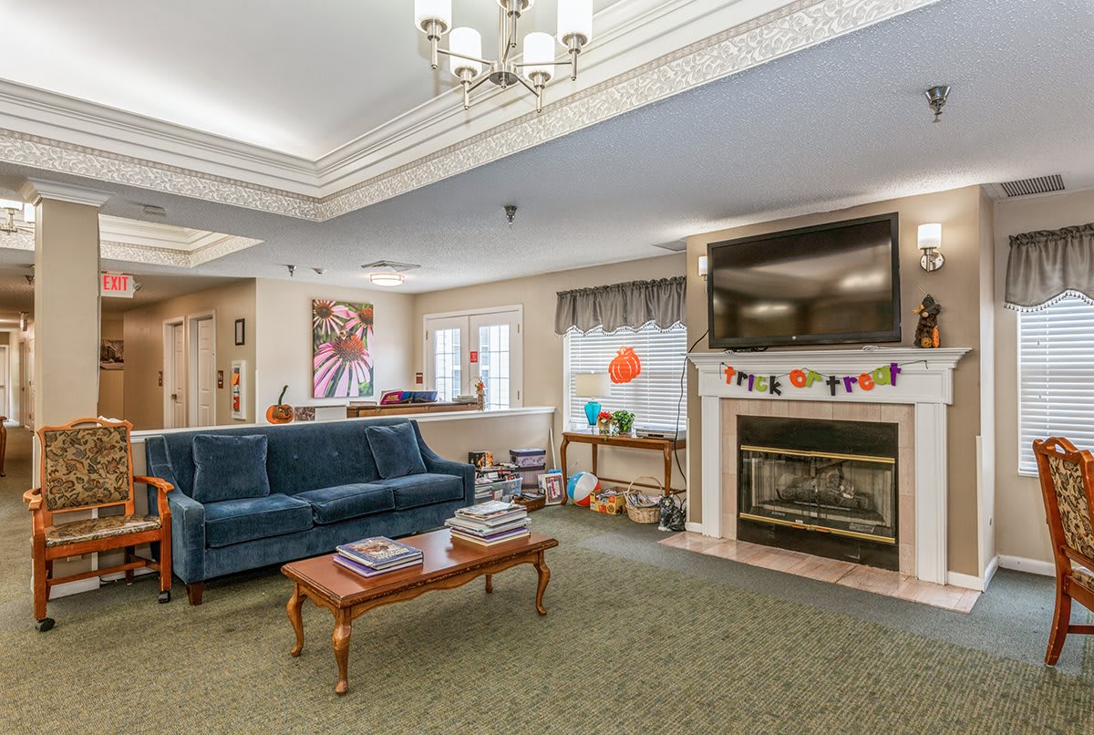 A cozy living room with a blue sofa, coffee table, and a fireplace under a wall-mounted television.