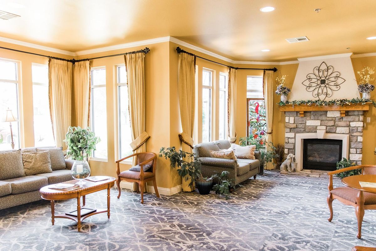 A cozy living room with a fireplace, sofas, and large windows letting in natural light.