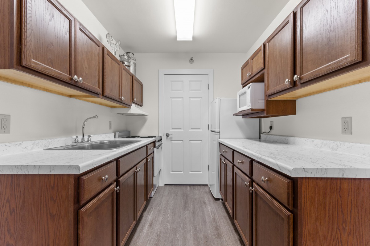 A modern kitchen with wooden cabinets and a sleek floor design.