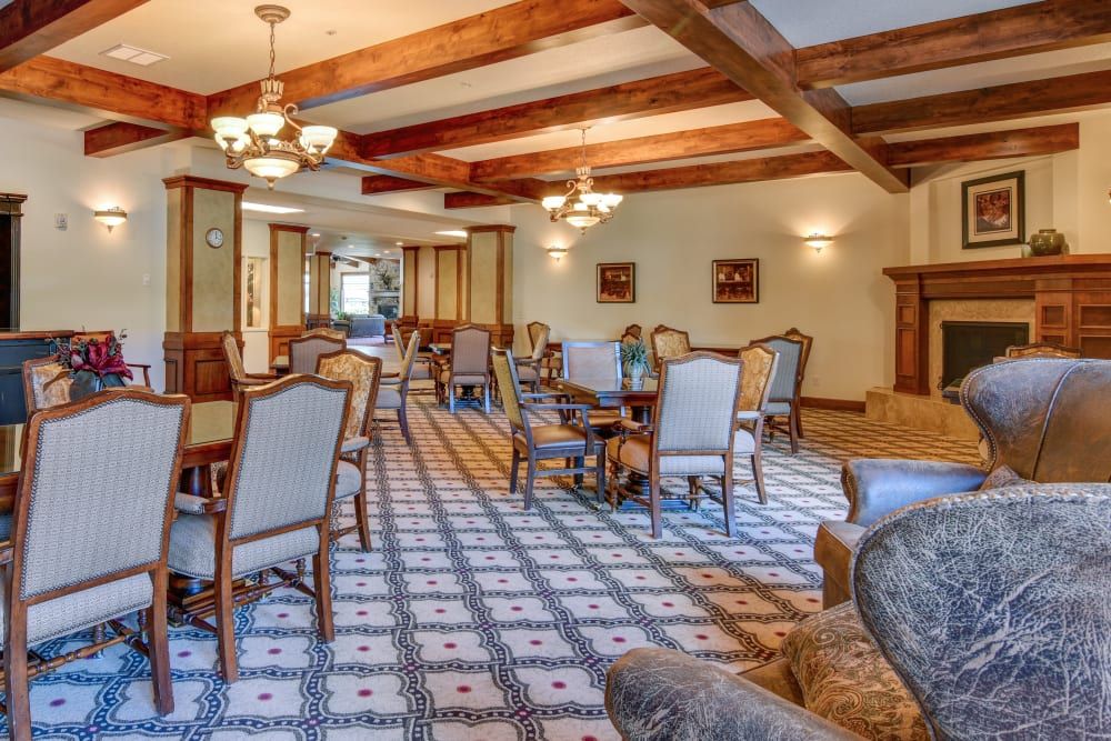 A spacious dining room featuring elegant furniture, chandeliers, and wooden ceiling beams.