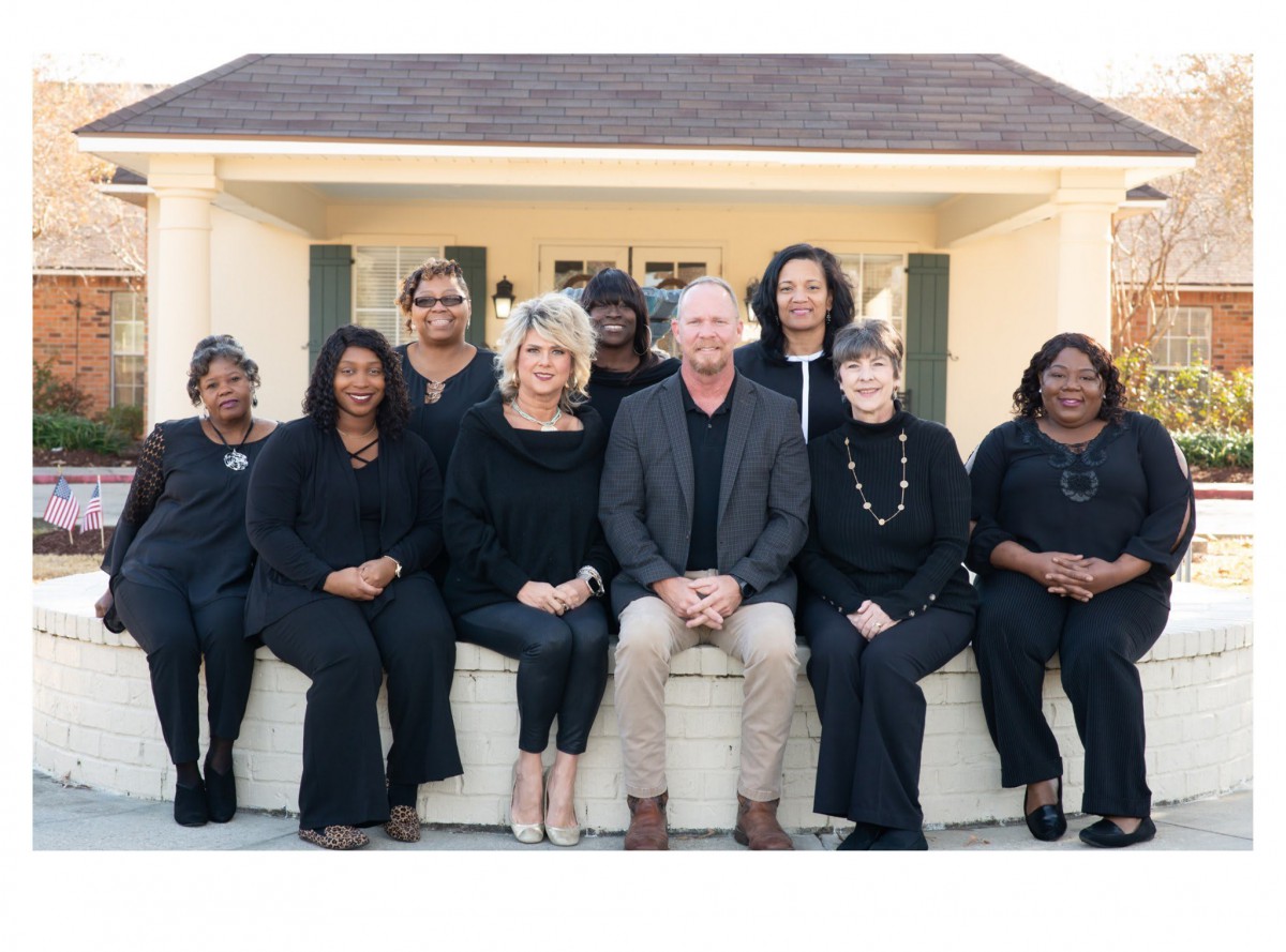 A group of people sitting together outdoors, posing for a team photo.